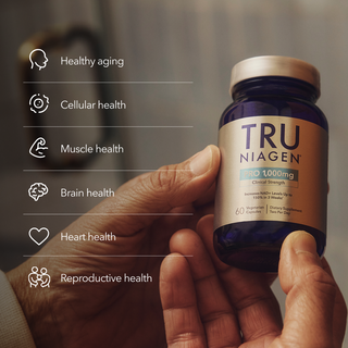 A hand holding the Tru Niagen bottle displayed against a blurred background, highlighting key health benefits: healthy aging, cellular health, muscle health, brain health, heart health, and reproductive health.