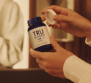 Person holding a bottle of Tru Niagen with a blurred background