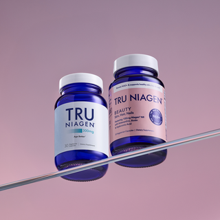 Tru Niagen® 300mg 30 count and Tru Niagen® Beauty supplement bottles on a reflective surface with a gradient purple background